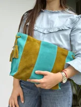 Cartera tipo sobre de cuero con diseño de rayas verticales en tonos verde menta y marrón tostado. Cuenta con detalles de borlas colgantes en los laterales.