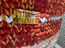 Bolso tejido a mano con hilo de trapillo, eco-cuero y textiles, con un diseño central de querubín coronado y alas, sobre un fondo de franjas rojas, blancas y azules. Posee asas cortas tejidas en color celeste claro.