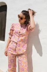 Camisa de lino con estampado floral en tonos rosados y naranjas, de corte recto, cuello mao y cierre frontal con botones. Presenta mangas al codo con frunces en los hombros.