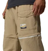 Pantalón convertible Columbia modelo Acker Rock Convert, color beige, de corte holgado y diseño cargo con múltiples bolsillos, bolsillos laterales con solapa y parche de la marca. Las perneras se desmontan mediante cremalleras para convertirlo en short.