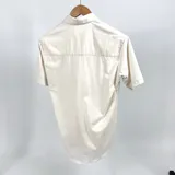 Camisa de manga corta color beige jaspeada con cuello común y cierre con botones.