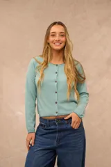 Saco de punto celeste de manga larga, con cuello redondo y cierre frontal de botones marrones. Presenta detalles de costura en contraste en el cuello, puños y ruedo.