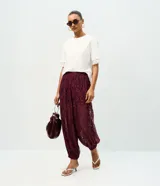 Pantalón aladín de encaje floral bordó, de calce amplio con cintura elástica y puños ajustados en los tobillos.