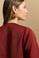 Blusa negra de satén con escote en V y detalle de volados frontales. Presenta mangas largas con puños abotonados y una silueta fluida.