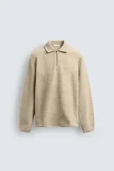 Sudadera de corte relajado confeccionada en tejido con textura, color beige. Presenta cuello solapa con cierre frontal de cremallera, manga larga y acabados con cinta elástica en puños y ruedo.