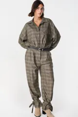 Pantalón de tiro medio con estampado a cuadros, corte holgado y pinzas en la cintura. Presenta un diseño distintivo con tiras ajustables en los tobillos que permiten crear un efecto fruncido.