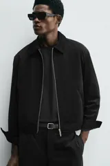 Sobrecamisa de corte cropped confeccionada en terciopelo con elasticidad. Presenta cuello solapa, cierre frontal con cremallera metálica, bolsillos de vivo en la cadera y mangas largas con puños abotonados.