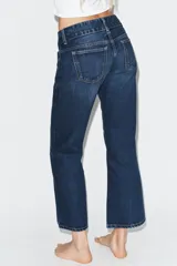 Jeans de tiro bajo y corte flare, confeccionados en denim azul con lavado localizado. Presentan bolsillos de plastrón en el delantero, trabillas para cinturón y cierre frontal con cremallera y doble botón metálico.