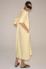 Vestido midi camisero de algodón, color amarillo con estampado a cuadros. Cuenta con cuello solapa, escote en V, mangas cortas con puño y bolsillos laterales ocultos en la costura, con diseño evasé.