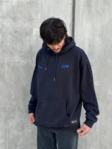 Canguro negro con capucha ajustable con cordones, bolsillo tipo canguro y logo bordado en azul en el pecho.