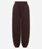 Pantalón estilo aladín de corte amplio y holgado, color marrón chocolate. Confeccionado en tejido de moletón con felpa interna, cuenta con cintura elástica y puños elásticos en los tobillos.