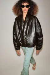 Cazadora acolchada Zara de efecto piel en color negro, con cuello en pico, manga larga, bolsillos delanteros y cierre frontal cruzado con botón.