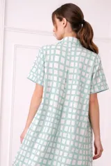 Camisa maternal de manga corta con diseño holgado, confeccionada en viscosa suave. Presenta un estampado de cuadros grandes en color rojo y crema, cierre frontal con botones y bolsillos laterales.
