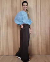 Pantalón de jean color beige, de corte recto y tiro alto, con ruedo deshilachado y cierre frontal con botón y cremallera.