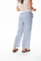 Pantalón largo a rayas verticales azules y blancas, con botón de coco, cintura elastizada y plizado en el bolsillo.