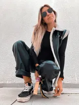 Chaleco negro de cuerina con interior de corderito sintético, bolsillos frontales y hebillas decorativas.