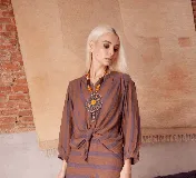 Camisa de lino con estampado de rayas horizontales en tonos marrones y violetas. Presenta cuello mao, cierre frontal con botones y mangas tres cuartos con frunces que aportan volumen.