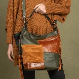 Cartera bandolera de cuero vacuno con diseño de patchwork en tonos verde, tostado y tabaco. Tiene una manija corta y una correa larga ajustable. Cuenta con dos bolsillos verticales con cierre en los laterales, un bolsillo con cierre en la parte trasera y un bolsillo con cierre y otro para el móvil en el interior.