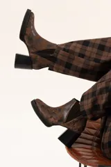Bota tipo chelsea de cuero con acabado texturizado efecto desgastado en color chocolate. Presenta paneles laterales elásticos, suela de plataforma y taco cuadrado robusto en color negro.