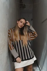 Sweater tejido a rayas horizontales color beige, marrón y negro, de cuello alto y corte holgado.