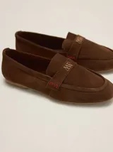 Mocasines de gamuza color tostado, de punta fina y diseño clásico, con detalle de antifaz en el empeine con el logo de la marca grabado.