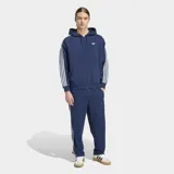 Campera con capucha Adidas Adicolor de corte holgado, color azul con cierre frontal de cremallera. Presenta las icónicas tres rayas blancas en las mangas y el logo del trébol bordado en el pecho.