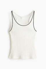 Musculosa blanca de punto acanalado suave, con escote en U y ribetes negros en contraste en el cuello y las sisas.