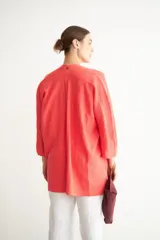 Sobre de mano confeccionado en cuero agamuzado con cierre metálico superior y correa lateral pequeña. Presenta un diseño minimalista con detalles de remaches metálicos en los extremos del cierre.