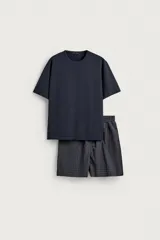 Set de pijama compuesto por una remera lisa de manga corta con cuello redondo y una bermuda a cuadros con bolsillos laterales y cintura elástica.