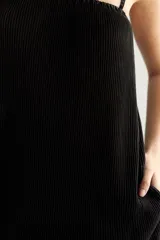 Vestido corto negro, de corte recto y suelto, con breteles finos y escote elástico. El tejido presenta un plisado vertical.