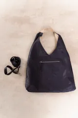 Bolso hobo reversible color azul marino, con textura símil cuero y correa bandolera extraíble.