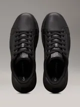 Zapatillas urbanas de cuero granulado color negro, con suela cupsole gruesa, interior de espuma, forro de malla de poliéster y logo de Calvin Klein en la lengüeta y el talón.
