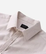 Camisa de manga larga con cuello inglés y cierre frontal de botones, confeccionada en tricolina de algodón color beige.