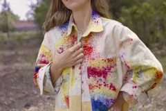 Chaqueta color beige con estampado abstracto en tonos amarillos, con cuello camisero, cierre frontal con botones, bolsillos plaqué y puños camiseros.