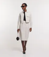 Falda midi color crema, de corte recto, con bolsillos laterales y cierre frontal.