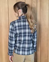Camisa de algodón con estampado de rayas verticales finas, cuello alto con volados, cierre frontal con botones dobles y mangas largas con puños elásticos terminados en volados.
