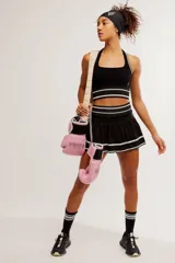 Conjunto deportivo compuesto por un top halter y una pollera pantalón de color blanco con líneas horizontales verdes.
