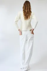Chaqueta de punto color negro, con escote en pico, manga larga y cierre frontal con botones dorados. Presenta un diseño con bajo asimétrico.