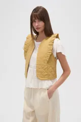 Chaleco acolchado de algodón en color mostaza, con diseño capitoneado y volados en los hombros.