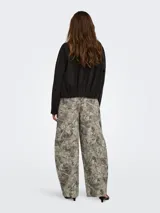 Pantalón de tiro alto con silueta barrel, más amplia en la rodilla y entallada hacia el ruedo, con estampa de efecto camuflado en tonos grises y verdosos.