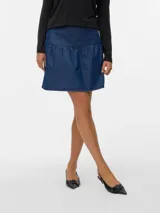 Pollera corta de denim azul medio, con tiro medio y cierre de cremallera. Presenta un diseño con un volante fruncido en el ruedo.