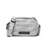 Bandolera gris de nylon con textura arrugada, de formato rectangular y cierre superior. Cuenta con correa ajustable y desmontable, bolsillos con cierre y un aplique frontal con el logo de la marca en relieve.