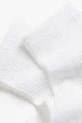 Pack de cinco pares de medias tobilleras blancas en punto acanalado suave con borde superior elástico.