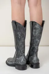 Bota de cuero vacuno color marrón oscuro, de caña alta, punta cuadrada y cierre lateral interno.