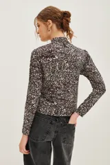 Polera de manga larga con cuello alto, confeccionada en tejido de algodón con estampado floral tipo liberty en tonos oscuros.