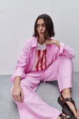 Pantalón de tiro alto con silueta amplia y caída fluida, confeccionado en tejido celeste con textura a rayas finas. Cuenta con cintura elástica con lazo de ajuste y bolsillos laterales.