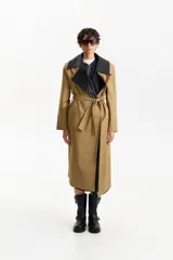 Gabardina larga color camel de silueta recta, con cuello de solapa ancha en contraste de piel sintética negra. Posee mangas largas, bolsillos laterales con solapa y cinturón a juego para ajustar a la cintura.