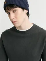 Sweater de punto con textura waffle, color negro, de corte clásico con cuello redondo y mangas largas con puños ajustados.