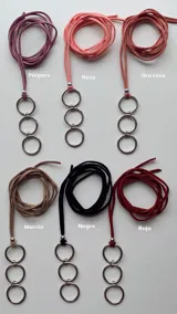 Gargantilla tipo choker confeccionada en cordón de símil gamuza negro, con dije colgante compuesto por tres argollas metálicas plateadas entrelazadas.