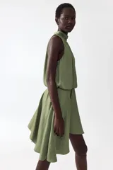 Vestido corto verde oliva con leve brillo, cuello halter elevado con frunces, cuerpo holgado con cintura elástica y falda corta de corte asimétrico.
